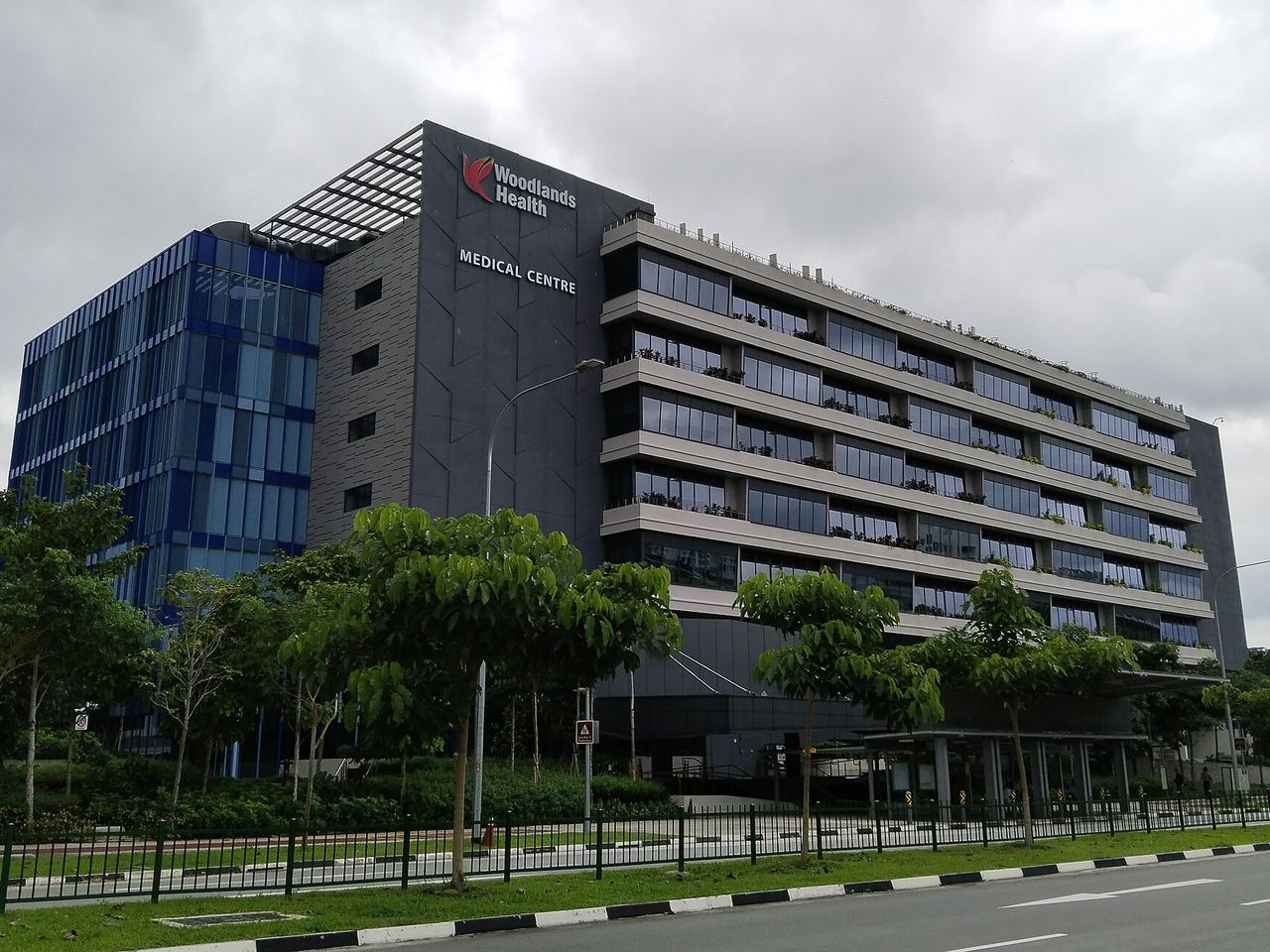 Woodlands Health Campus medical centre building beside a tree-lined road