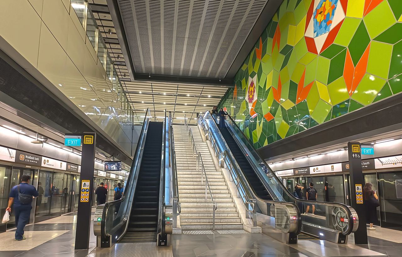Escalators and the green mosaic art wall inside Woodlands South MRT station on the Thomson-East Coast Line
